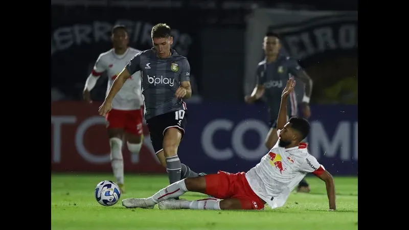 Cầu thủ của Platense với chiếc áo đỏ đang cố gắng chặn đứng đối thủ từ Deportivo Riestra…
